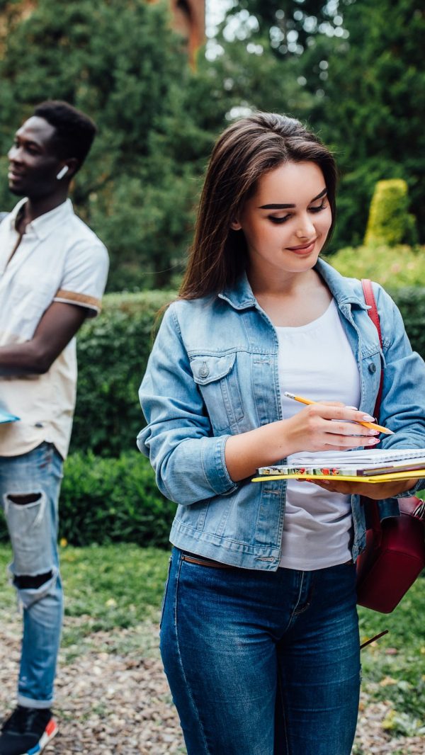 Three students talking to each other outdoor in a college courtyard.